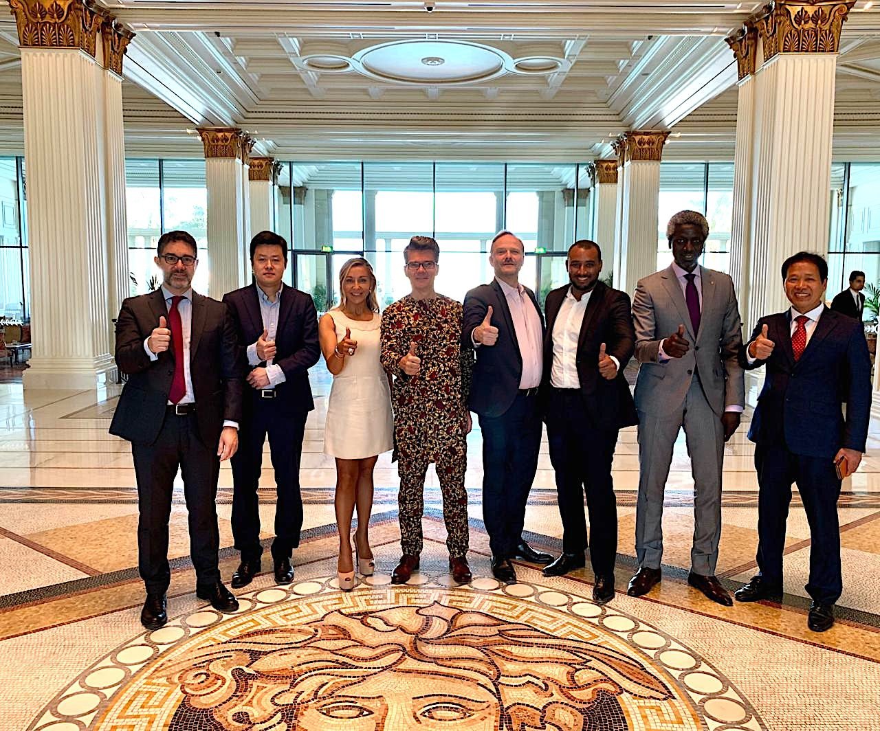 Group of professionals, including the One Ace representative, posing with Cleantech Business Club network partners at the Palazzo Versace entrance.