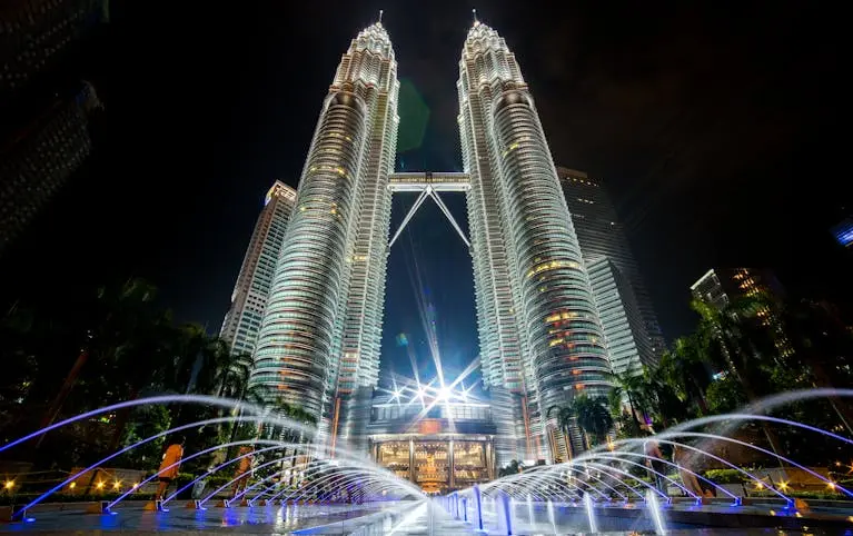 Stunning night view of the illuminated Petronas Twin Towers in Kuala Lumpur with fountains in the foreground.