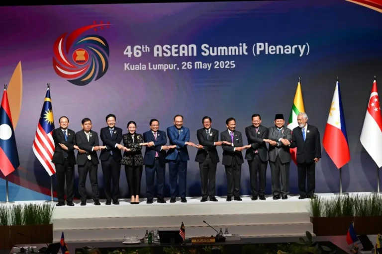 ASEAN Heads of State and Government holding hands at the 46th ASEAN Summit in Kuala Lumpur, May 26, 2025, in front of national flags.